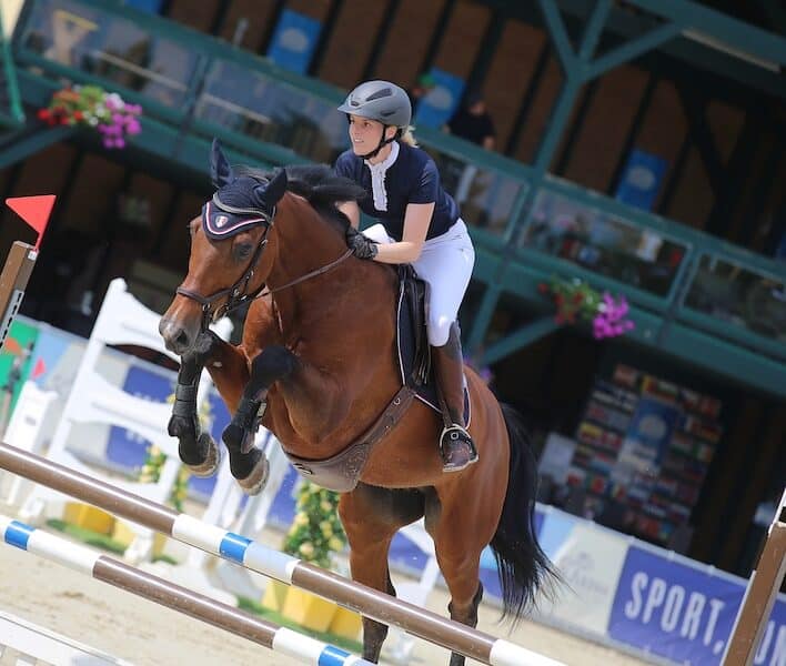 Ingrid Königshofer springt auf einem Pferd über ein Hindernis. Pferdesport